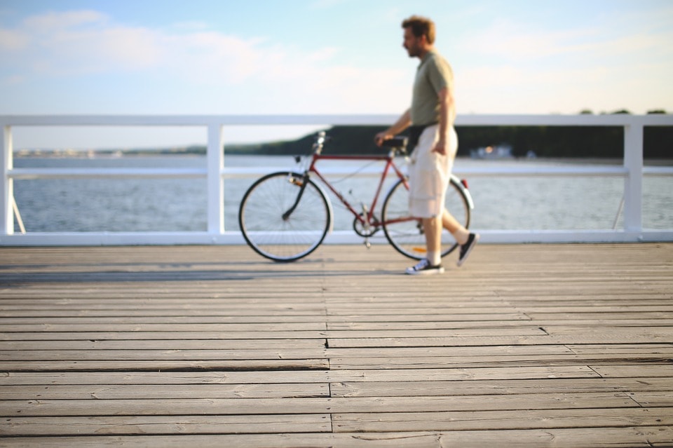 man walks his bike on the boardwalk