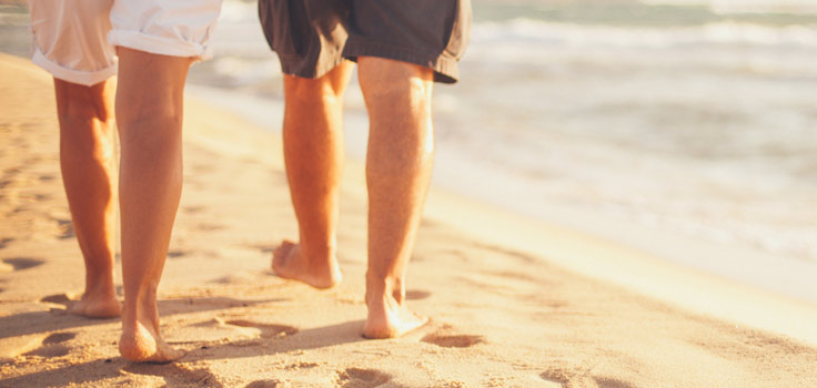 two people walking on the beach. exposed legs
