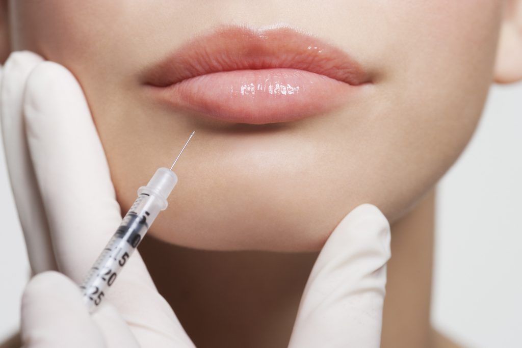 woman getting filler injection in her lower lip
